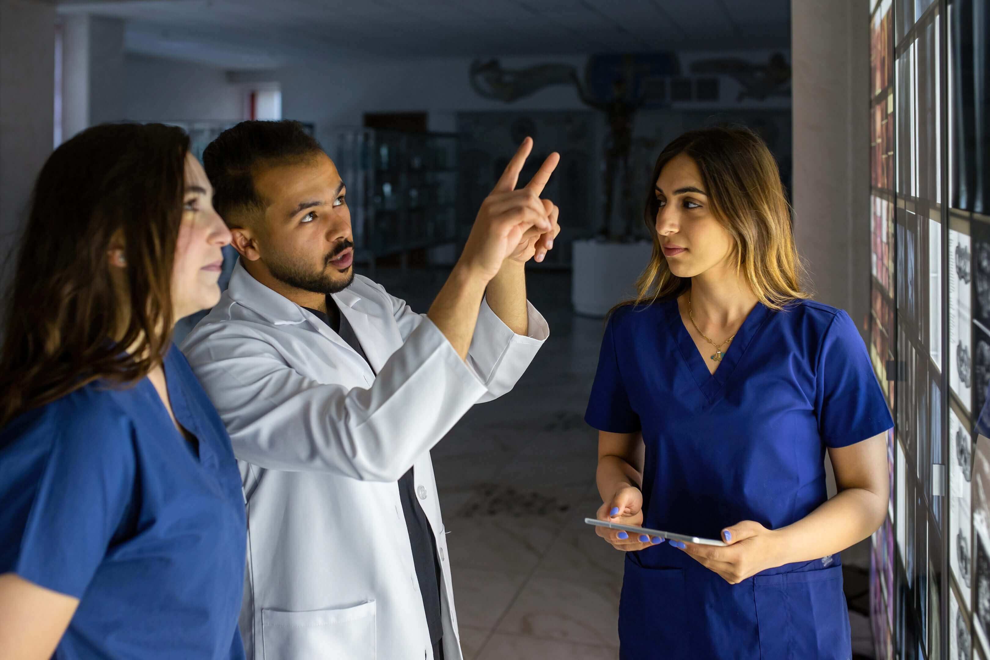 Doctors discussing medical images on screen.
