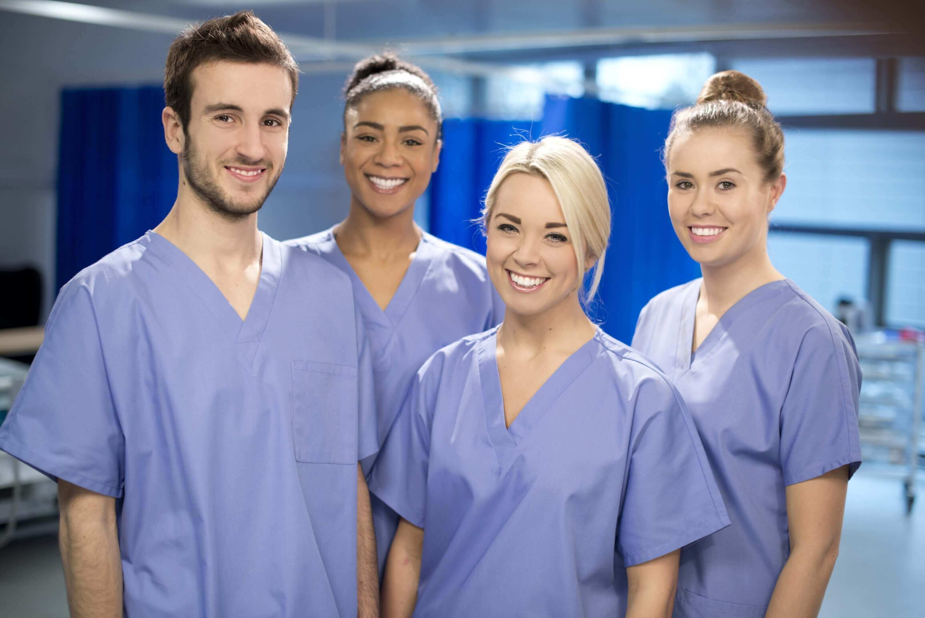 A group of smiling healthcare workers in blue scrubs.