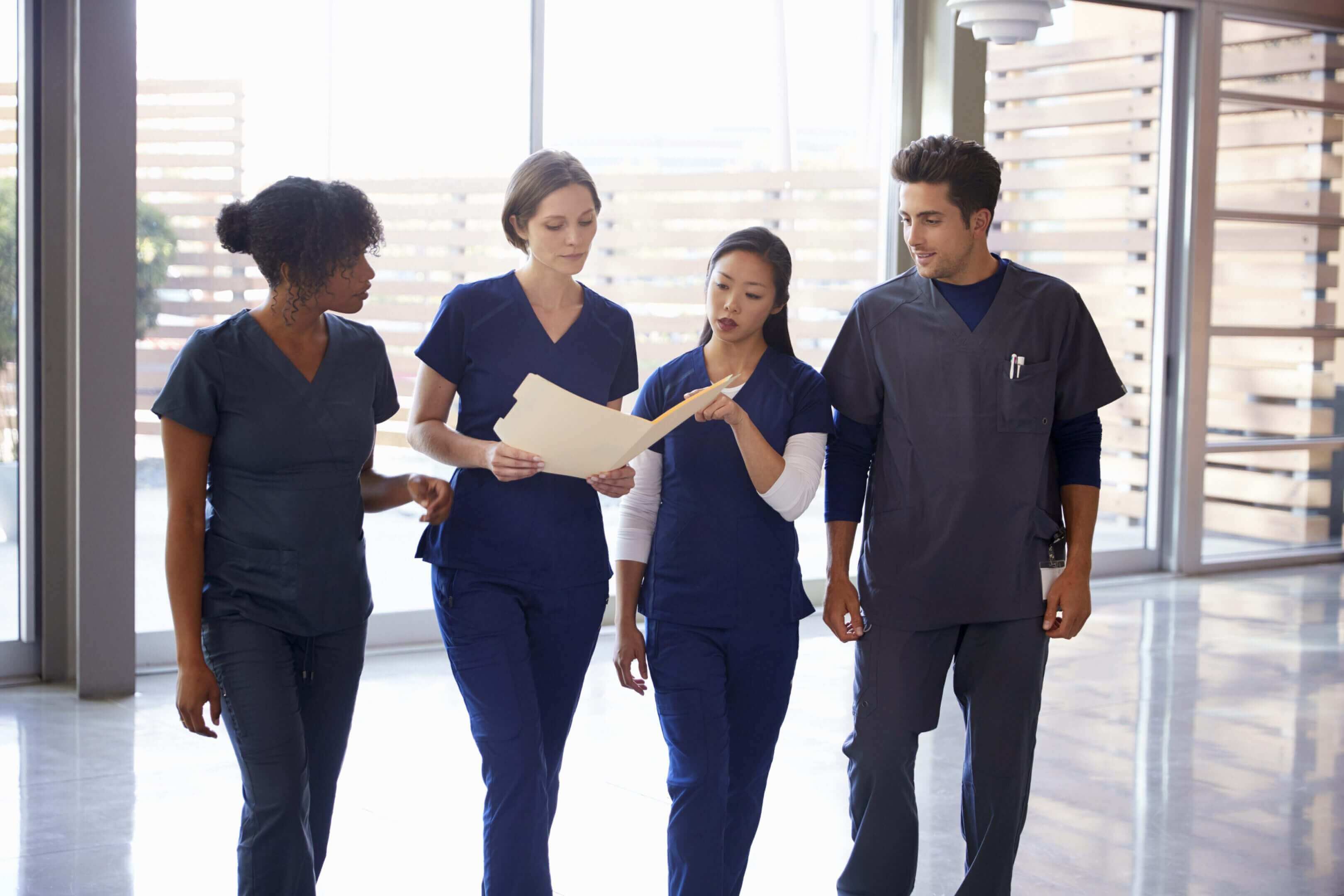 Healthcare professionals walking and discussing in a hospital corridor.